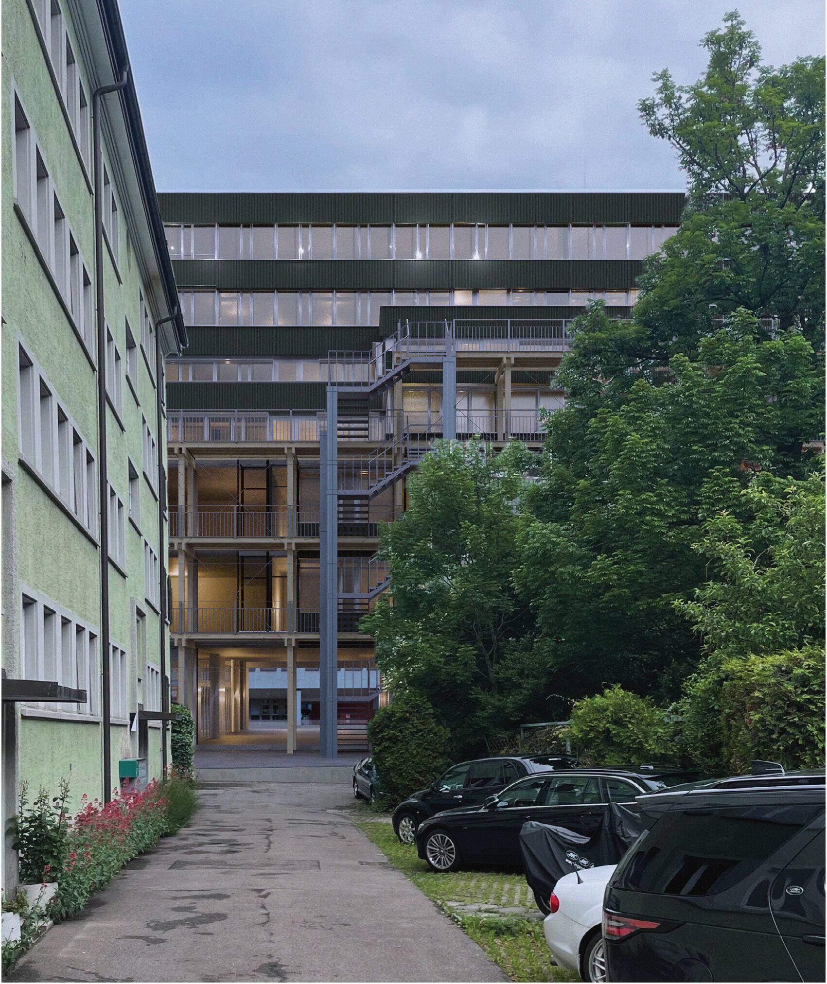 View from the residential backyard towards the transformed industrial building at dusk