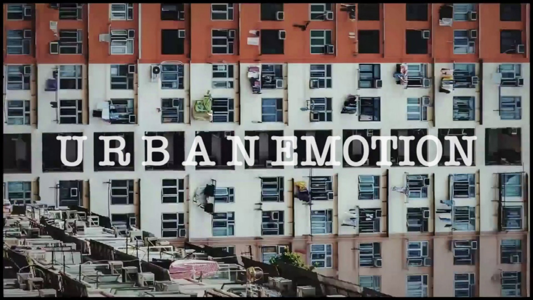 Film still: Urban Emotion title over a dense facade